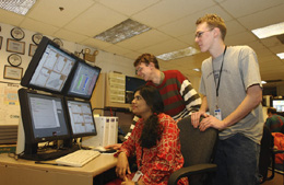  'We initiated the remote international monitoring as an opportunity to take part in activites in the Control Room for collaborators who can't travel frequently to the lab. It's a good way for them to participate and to know what's going on here,' said Pushpa Bhat, viewing the DZero Global Monitoring System with Michiel Sanders (center) and Jason Webb (right). Webb, an undergraduate student at DeVry University, developed the messenger system for communication with remote shifters. Sanders, of the University of Manchester in England, helped develop on-line monitoring tools.