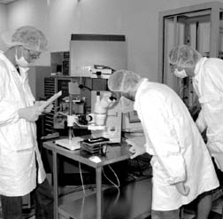 Peter Van Gemmeren, Eric Kajfasz and Frank Lehner using a microscope to check the condition of a silicon detector.