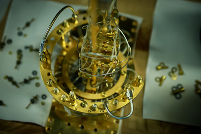 An assembly for the cryogenic dilution refrigerator sits half built on the technician's desk