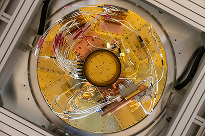 Looking up into the belly of a quantum computer at the SQMS Garage at Fermilab. The cryostat insulating jacket has been removed, revealing the golden interior.